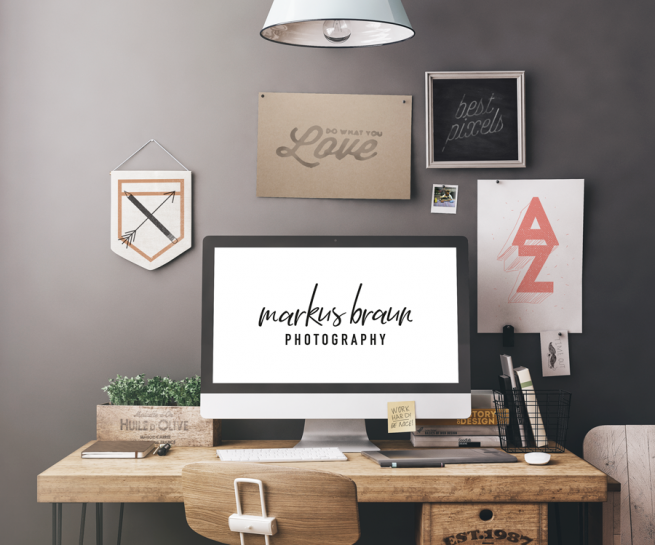 Arbeitsplatz mit großem Bildschirm der das Logo von Markus Braun Photography zeigt