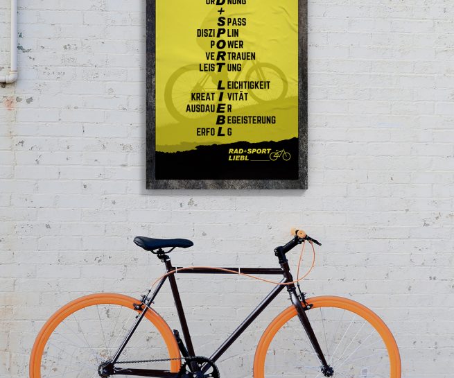 Fahrrad vor Steinwand mit gelbem Poster von Rad+Sport Liebl Senden