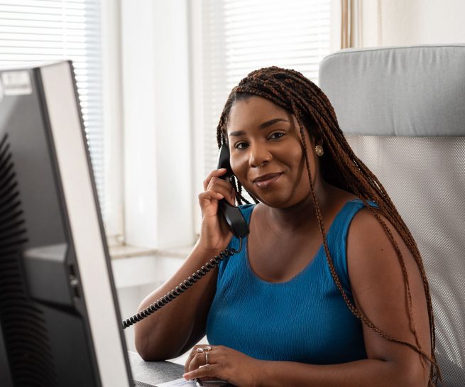 Person am Arbeitsplatz mit Telefonhörer in der Hand